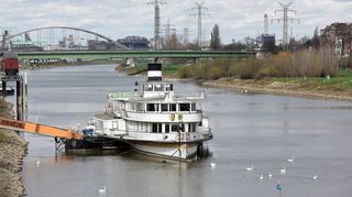 Das Museumsschiff liegt am nördlichen Neckarufer zwischen Kurpfalzbrücke und Jungbuschbrücke (im Hintergrund). Am Ufer gibt es noch mehrere Exponate zur Hafengeschichte, etwa den Kran links.