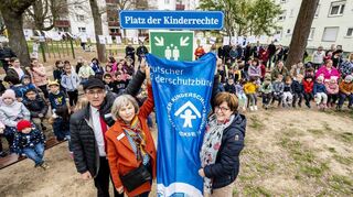 Stadt und Kinderschutzbund setzen ein Zeichen für die Rechte von Kindern und eine kinderfreundliche Gesellschaft und weihen den Platz „Grüne Mitte“ an der Quartiersmensa in Speyer-West als zweiten Platz der Kinderrechte in Speyer ein. Gerade enthüllen der zweite Vorsitzende Hartmut Loos, die Vorsitzende Christel Koch und Bürgermeisterin Monika Kabs das Schild.