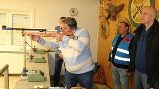 Die Teilnehmer des Ostereierschießens zielen mit dem Luftgewehr auf eine zehn Meter entfernte Papierscheibe.