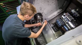 Ein junger Werkzeugmechaniker arbeitet an einer Drehmaschine.