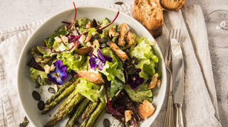 Ofen statt Topf: Grüner Spargel vom Blech kann auch in einer Bowl mit Blattsalat, essbaren Hornveilchen und Kürbiskernen landen. Dazu passt Ciabatta-Brot.