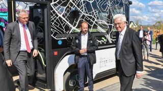 Winfried Kretschmann (ganz rechts) schaut sich das neuartige Fahrzeugkonzept U-Shift an, das auf der Buga im Forschungsbetrieb läuft.