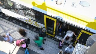 Zugreisende stehen am Bahnhof, um in den Zug einzusteigen.