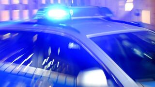 Ein Streifenwagen der Polizei steht mit eingeschaltetem Blaulicht auf der Straße.