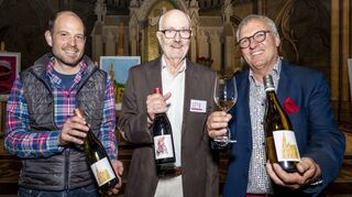 Gerne zeigen Winzert Volker Gies, der zweite Vorsitzende des Bauvereins Helmut Peter Koch und der die Etiketten gestaltende Künstler Oliver Schollenberger die Weine vor dem Altar stehend.