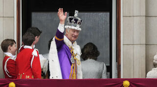 König Charles III. winkt nach der Krönungszeremonie vom Balkon des Buckingham Palastes aus der Menge zu.