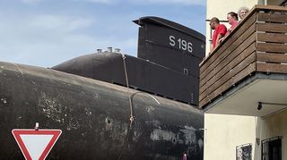 Biegt ein U-Boot um die Hausecke: Bewohner schauen auf dem Balkon zu, wie das 500 Tonnen schwere Gerät durch die Kurve navigiert wird.