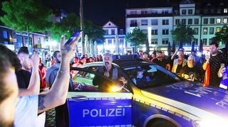 Ein Mann beschwichtigt aufgebrachte Feiernde am Marktplatz.