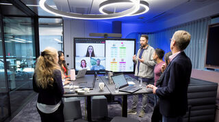 SAP-Beschäftigte besprechen ein Projekt. Kolleginnen und Kollegen sind auch online zugeschaltet.