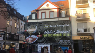Ein riesiges Transparent an der Fassade des Gebäudes in H 1 warb für das neue Restaurant am Marktplatz.