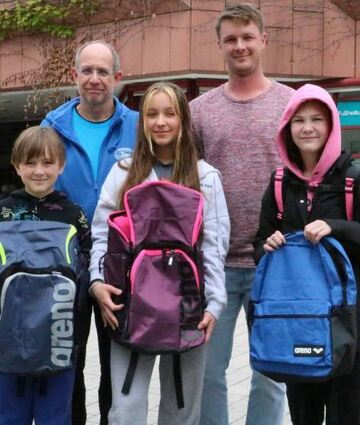 Timur, Arina und Eva (vorne, v. l.) zeigen stolz ihre Rucksäcke. Hinter ihnen freuen sich Michael Hintze und Nicolas Hoock (r.).