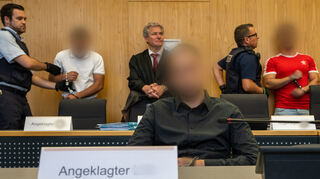 Die Angeklagten werden von Justizwachtmeistern in den Sitzungssaal im Landgericht Ulm geführt. Drei junge Männer müssen sich wegen versuchten Mordes nach einem Angriff auf einen Polizisten vor der Jugendkammer verantworten. Sie sollen das Opfer in einen Hinterhalt gelockt und zu Boden geprügelt haben. Der Polizist überlebte schwer verletzt. Die Staatsanwaltschaft wirft den Angeklagten versuchten Mord und gefährliche Körperverletzung vor.