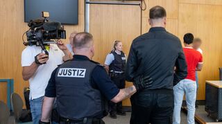 Die Angeklagten im Prozess um einen Angriff auf einen Mannheimer Polizisten werden in den Sitzungssaal im Ulmer Landgericht geführt.