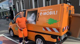 Salih Mohr mit Greifzange und Müllbeutel vor einem der sechs modernen Elektro-Kleinkehrrichtfahrzeuge, die sich die Stadt zugelegt hat.
