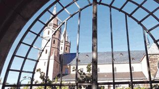 Blick durch das Portal des verschwundenen Kreuzgangs auf Reben und die Liebfrauenkirche. Das Foto symbolisiert die jahrhundertelange Verbundenheit zwischen Gotteshaus und Wein.