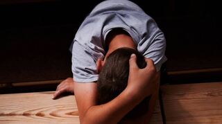 Ein Kind versteckt sein Gesicht und liegt mit dem Kopf auf einem Tisch (gestellte Szene). Sexuelle Gewalt kann ein Trauma für das ganze Leben sein.