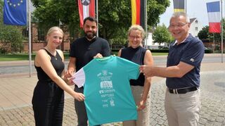 Celine Janda, Dominik Nagel (beide EWR), Sabine Gärtner (TVL) und Bürgermeister Gottfried Störmer präsentieren das Finisher-T-Shirt für den Spargellauf.