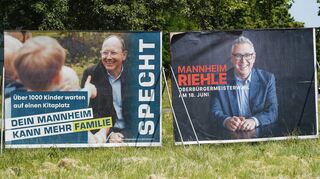 Wahlplakate von Christian Specht (l.) und Thorsten Riehle stehen nebeneinander auf einer Wiese.