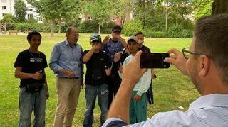 Volker Proffen fotografiert Christian Specht mit einer Gruppe Jugendlicher. Die jungen Männer feiern seine Ankunft im Neckarauer August-Bebel-Park.