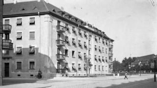 Auf der historischen Aufnahme, die ungefähr im Jahr 1930 entstanden ist, sieht man rechts im Hintergrund ein Gebäude des Klinikums.