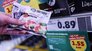 Zwei Preisschilder hängen im Penny-Kühlregal beim Mozzarella. Eines berücksichtigt verdeckte Kosten, etwa für Umweltverschmutzung bei der Produktion.