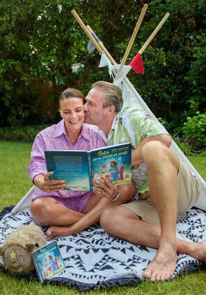 Sänger Sasha und seine Frau Julia Röntgen sitzen mit dem Kinderbuch "Toto und der Mann im Mond" vor einem Kinderzelt im Garten ihres Grundstücks. Für das Buch und das dazugehörige Album mit Musik des Sängers haben seine Frau und er sich von ihrem gemeinsamen Sohn Otto inspirieren lassen.