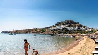 Trotz Waldbränden kommen weiterhin Touristen zum Urlaub machen nach Rhodos, wie hier an den Strand in Lindos.