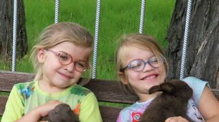 Die Zwillinge Paige und Annalena kuscheln mit ihren Kaninchen der Rasse Kleinsilber havannafarben.