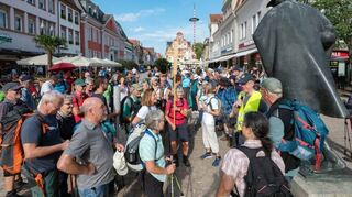 Die Pilgerinnen und Pilger auf ihrem Endspurt kurz vor dem Dom. Domkapitular und Regens Franz Vogelgesang spricht zu ihnen an der Figur des Jakobspilgers in Speyer.