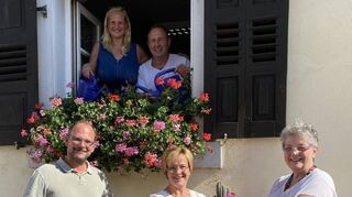 Während Sigrid und Wolfgang Geef (oben im Fenster) gießen, übergibt Heike Siegmann (unten Mitte) einen Stichler-Gruß an Michaela Diehl (rechts). Klaus Reuther (l.) half noch mit, die verblühten Blüten auszuzupfen.