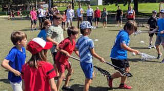 Alle gemeinsam für mehr Unterstützung des Ehrenamts im Sport: Darüber sind sich Vertreter von Politik und Verbänden (im Hintergrund) beim Austausch vor Ort im Römerstadion einig, hier bei einer Demonstration von Kindern im Lacrosse-Spiel.