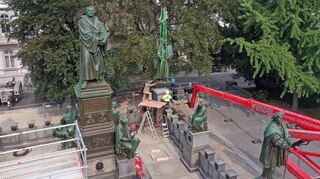 Philipp Melanchthon wird wieder an seinen Platz gehoben. Die Figuren auf dem Wormser Lutherdenkmal waren verrutscht.