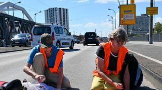 Ein Aktivist und eine Aktivistin der „Letzten Generation“ kleben ihre Hände auf die Konrad-Adenauer-Brücke.