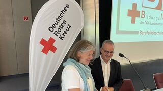 Klinik-Geschäftsführerin Susanne Dieffenbach (l.) und DRK-Vorstand Manuel Gonzalez besiegeln die Partnerschaft mit der Unterschrift eines Vertrags.
