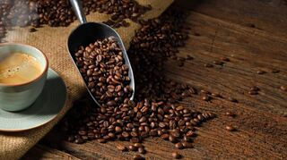 Cup of coffee with smoke and coffee beans on old wooden background