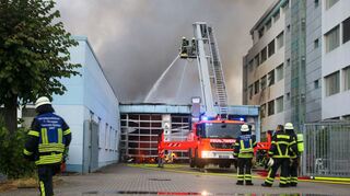 Einsatzkräfte der Feuerwehr löschen das Feuer in einer Wäscherei im Industriegebiet von Walldorf.