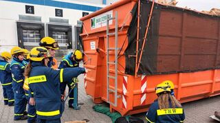 Zum Glück ist es nur eine Puppe, die die jungen Rettungskräfte hier unter dem Container herausholen müssen.