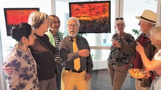 In der Ausstellung im Hallenbadcafé: Künstler Jürgen Richter (Mitte) erklärt sein Bild Inferno, gearbeitet in Acryl.