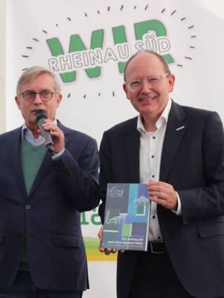 Siedlerchef Held (l.) überreicht OB Specht die Ortschronik.