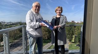 Wolf Wollstadt überreicht Jasmin Breit auf der Dachterrasse des Marchivums symbolisch einen seiner VDK-Ordner.