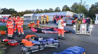 Der Rettungsdienst übernimmt die per Drehleiter vom Dach geholten Frauen, während die Flugplatzfeuerwehr ein Zelt zur Verletzten-Versorgung aufbaut.