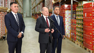Bundeskanzler Olaf Scholz (Mitte) mit den Brüdern Kadir Baklan (links) und Mustafa Baklan (rechts) von Suntat im Anschluss an seinem Besuch bei der Lebensmittelhandelsgesellschaft Suntat Europe GmbH in Mannheim.