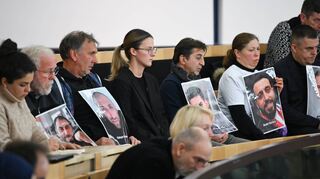 Angehörige der Opfer des rassistischen Attentats von Hanau halten auf der Besuchertribüne des Hessischen Landtags Fotos in die Höhe.