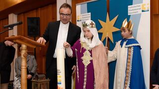 Beim Neujahrsempfang des katholischen Stadtdekanats entzündet Dekan Karl Jung mit Sternsingerin Alina Thoma die Jahreskerze.