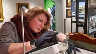 Restauratorin Christine Lincke platziert den Kristallpokal in der Ausstellung.