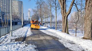 Ein Schneeräumfahrzeug der Stadt Mannheim ist auf dem Rad- und Fußweg am Neckarufer unterwegs.