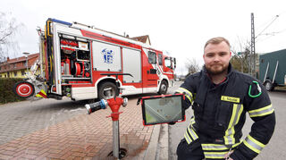 Initiator Lukas Nicolai zeigt den digitalen Hydrantenplan auf einem Tablet, dahinter ein Hydrant.