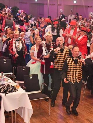 Gute Stimmung im Rosengarten: v. l. „Die Krähenfelder“ aus dem Rheinland führen die Polonaise im Saal an, dahinter das Prinzenpaar. In der Mitte Irmi Benz als Influencerin, rechts Stadtrat Alexander Fleck, diesmal in der Rolle des Richters.