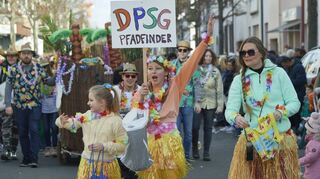 Bekleidet mit Hawaii-Röcken und mit Blumengirlanden um den Hals begrüßen die DPSG-Pfadfinder die Umzugsbesucher.