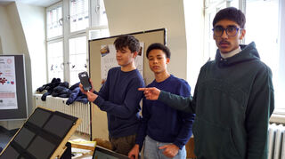 Philipp Juszczak (v.l.), Amani Michler und Vipin Kumas haben eine kleine PV-Anlage gebaut, um Smartphones klimaneutral im Klassenzimmer aufzuladen.